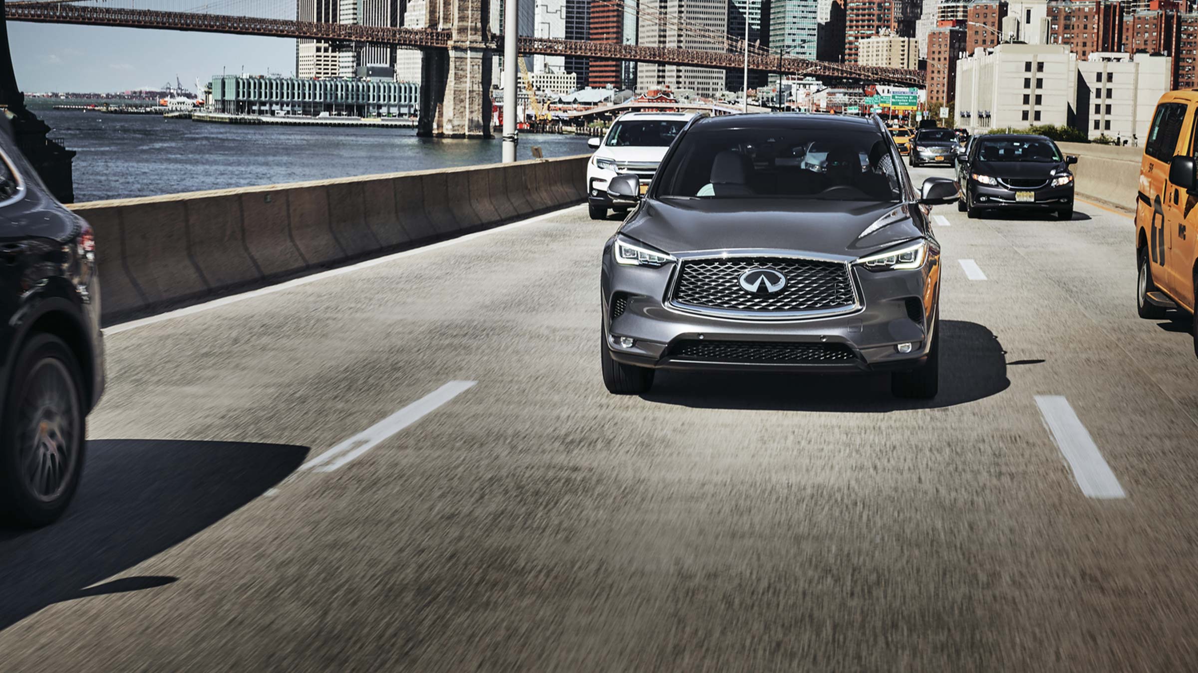 A front view of 2022 INFINITI QX50 SUV driving down a busy street.